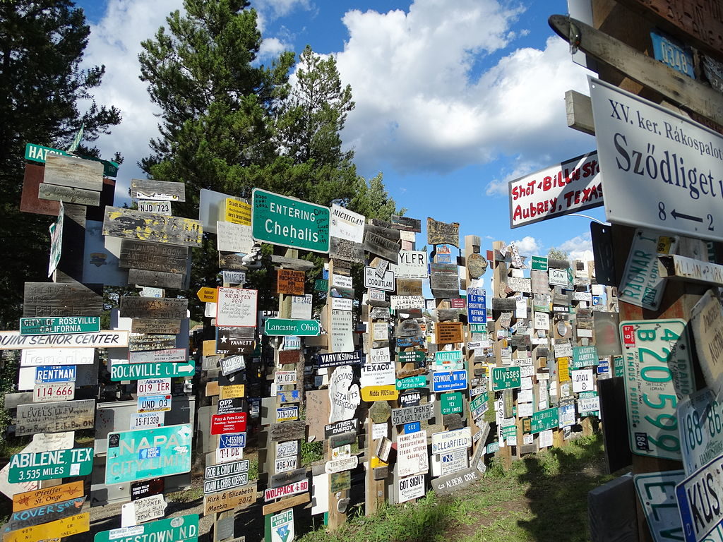 Rows of signs and license plates from around the world tacked to posts.