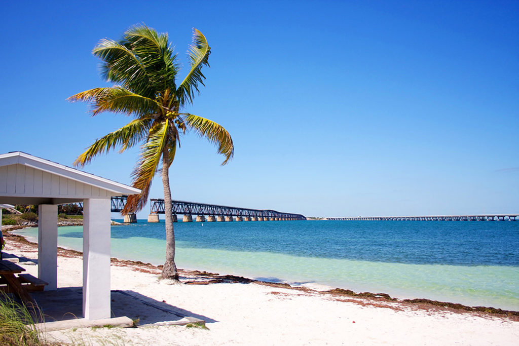 White sand beach at Bahia Honda State Park with the remnants of the Overseas Highway railway line visible out above the water.