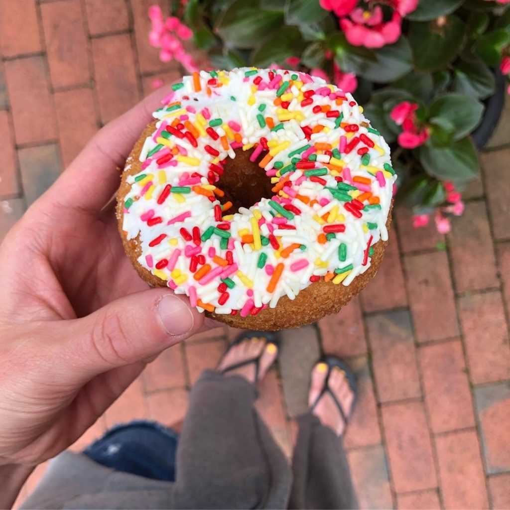 hand holding a donut with sprinkles