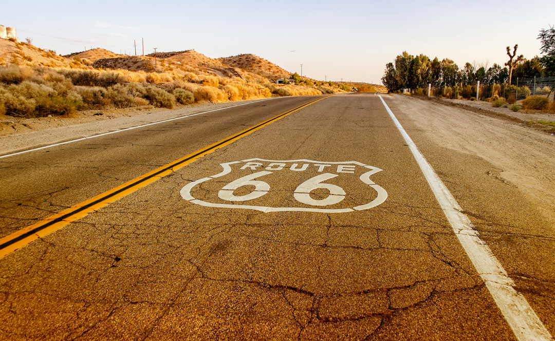 route 66 insignia on the road stretching through desert landscape