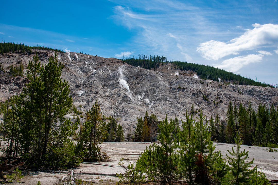 Image of the gray roaring mountains with steam and surrounding trees