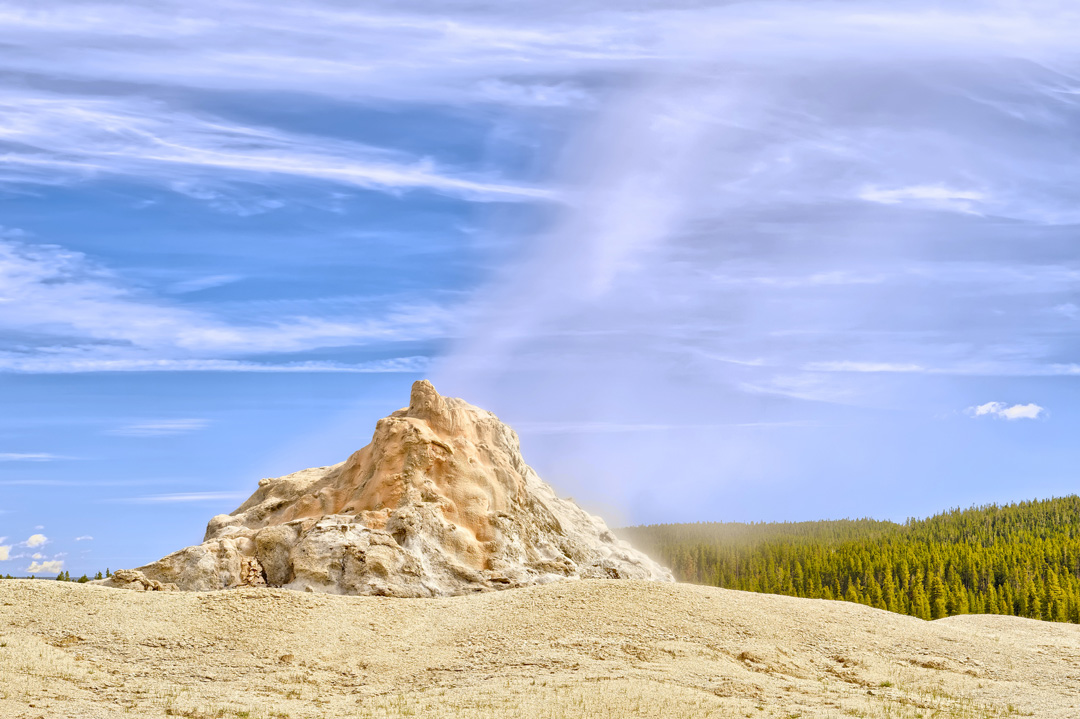 White Dome Geyser steaming under clear blue skies