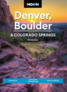 Cover of the Moon Denver, Boulder, and Colorado Springs travel guide featuring an image of a sunset over a rocky valley