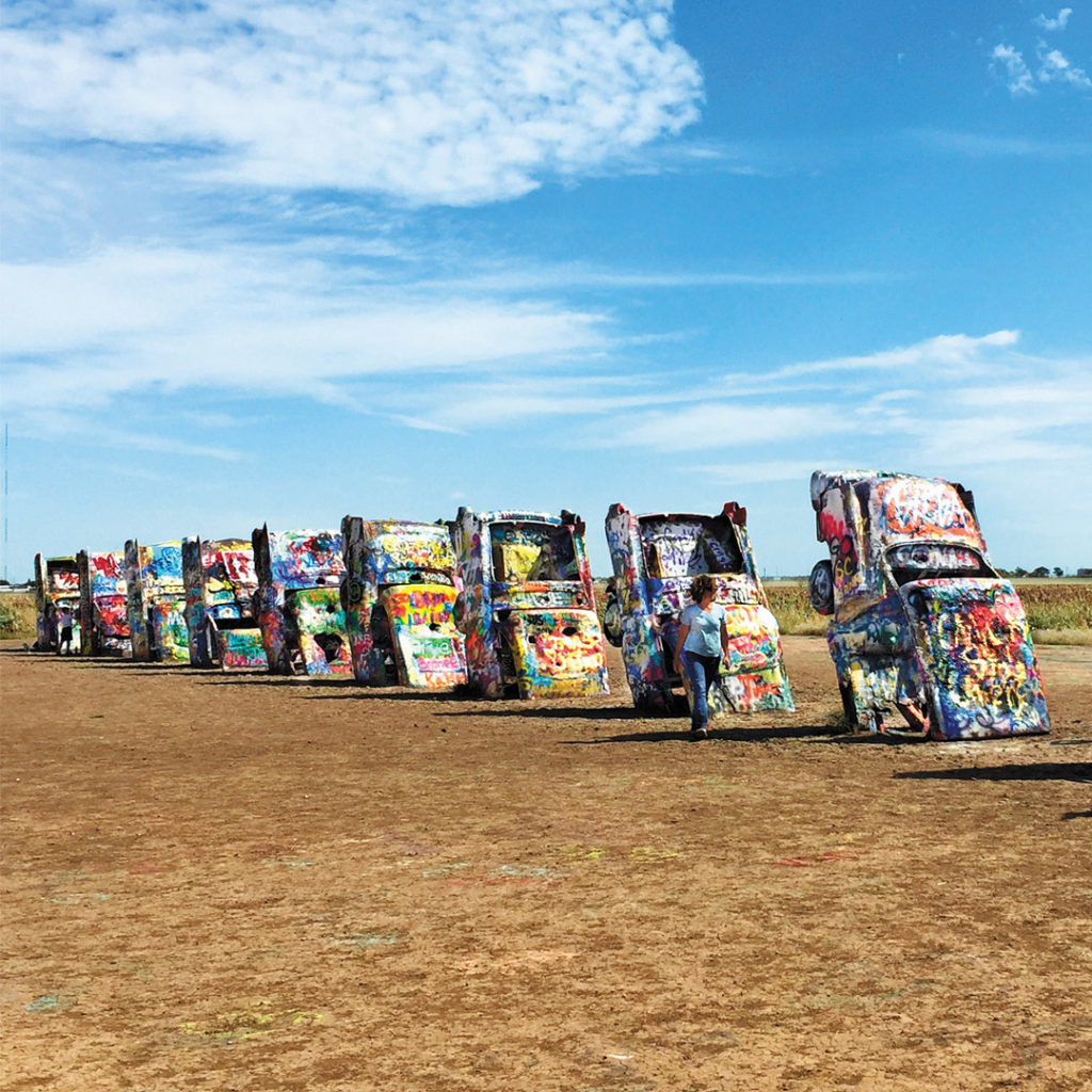 painted cars sticking out of the ground in a line