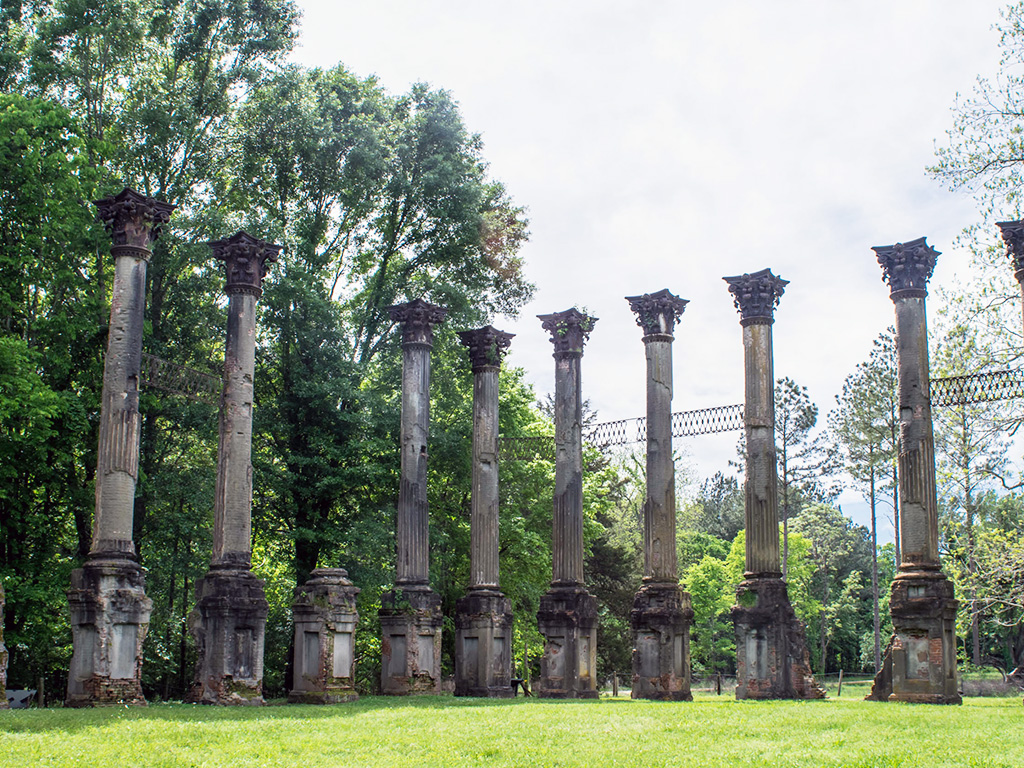 stone pillar ruins surrounded by trees and grass