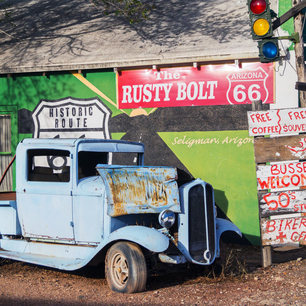 a rusty old truck in front of the rusty bolt sign