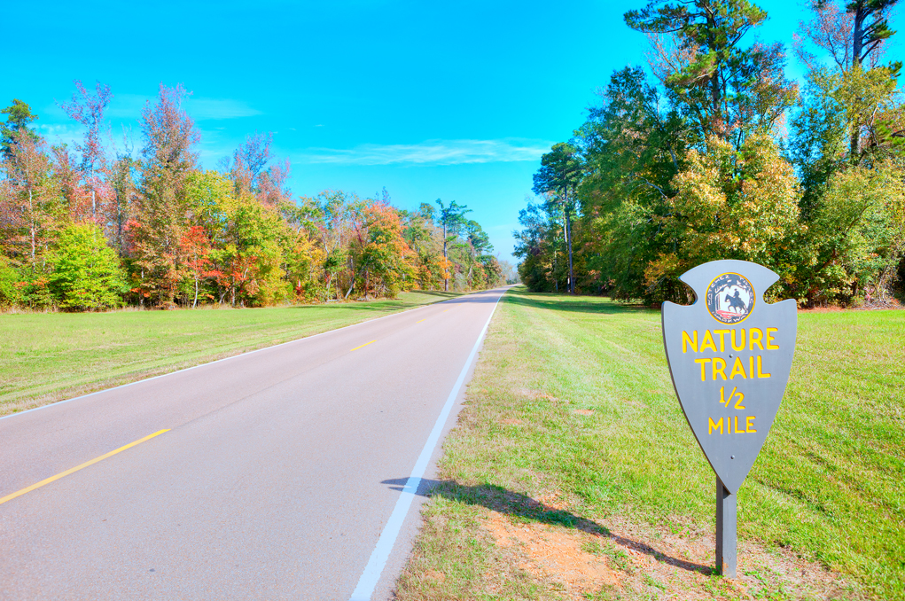 Photo of the highway with fall foliage and a sign that reads "nature trail"