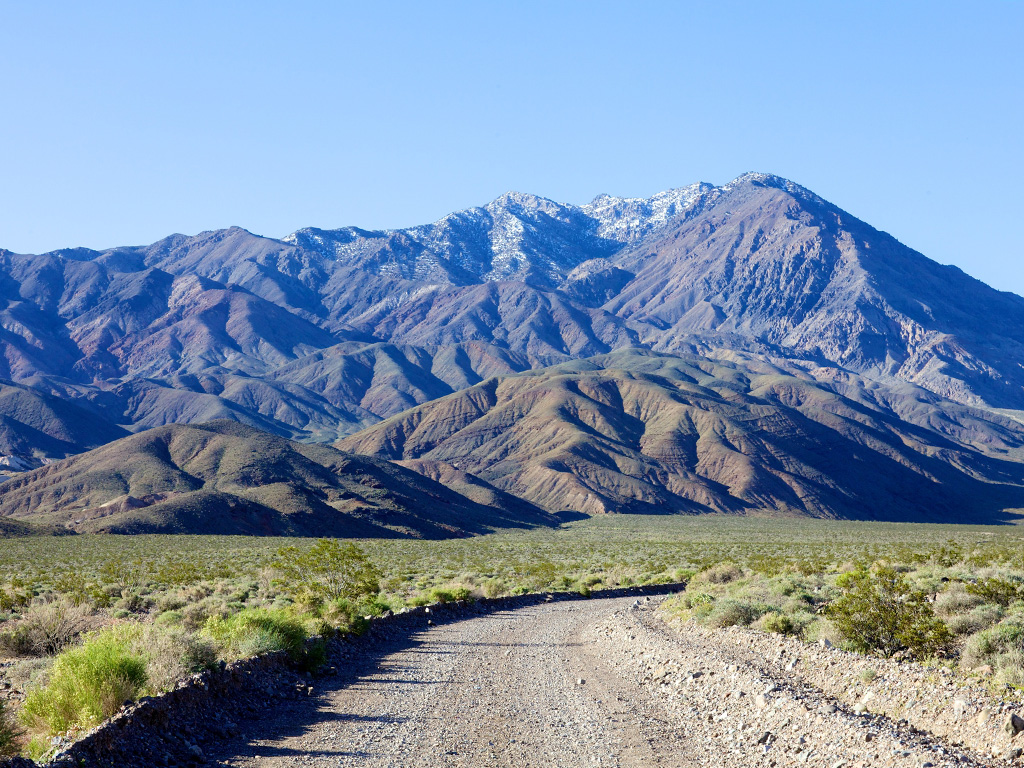 dirt road winding toward the mountains in death valley