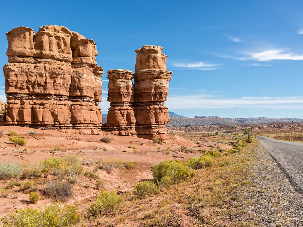 hoodoos on the side of a road through otherwise barren landscape in utah